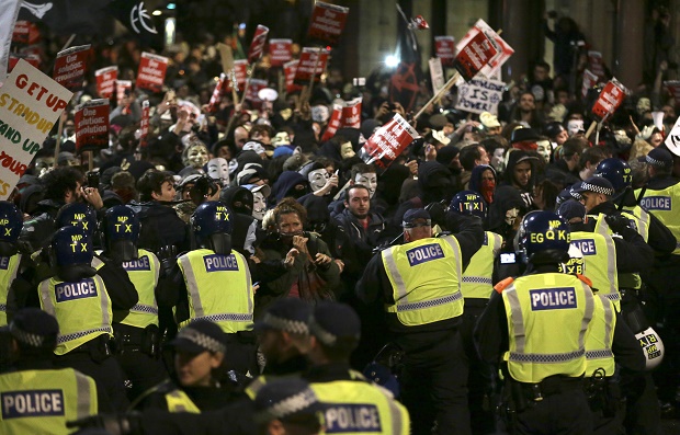 Police try and block masked demonstrators as they march in central London during the Million Mask protest march on Thursday Nov. 5, 2015. Thousands of people dressed in Guy Fawkes masks are being met by significant policing operation, including thousands of extra officers to tackle expected unrest in this annual march that coincides with the Nov. 5 Bonfire Night celebration.  (AP Photo/Tim Ireland)