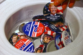 A guest at an event called the U.S. Presidential Election Watch, organised by the U.S. Consulate, reaches for a badge from out of a hat displaying photographs of Republican candidate Donald Trump and Democratic candidate Hillary Clinton, in Sydney